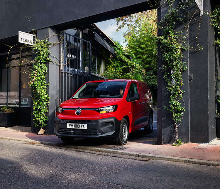 Новий фургон Citroën Berlingo виїжджає з двору на вулицю у місті